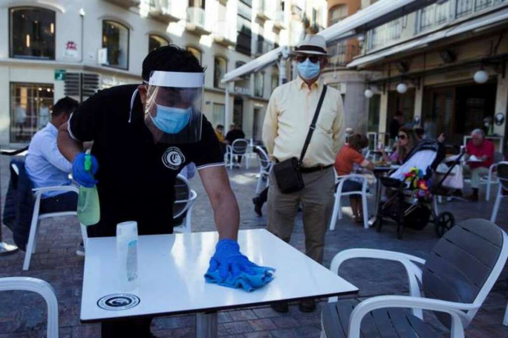 Un camarero limpia la mesa de una terraza antes de que se siente un cliente./ EFE