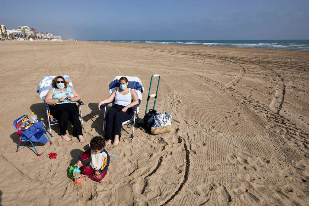 Varias personas toman el sol en la playa de Gandía (Valencia) con la mascarilla, de uso obligatorio incluso cuando se respeta la distancia de seguridad | EFE/NF