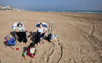 Varias personas toman el sol en la playa de Gandía (Valencia) con la mascarilla, de uso obligatorio incluso cuando se respeta la distancia de seguridad | EFE/NF