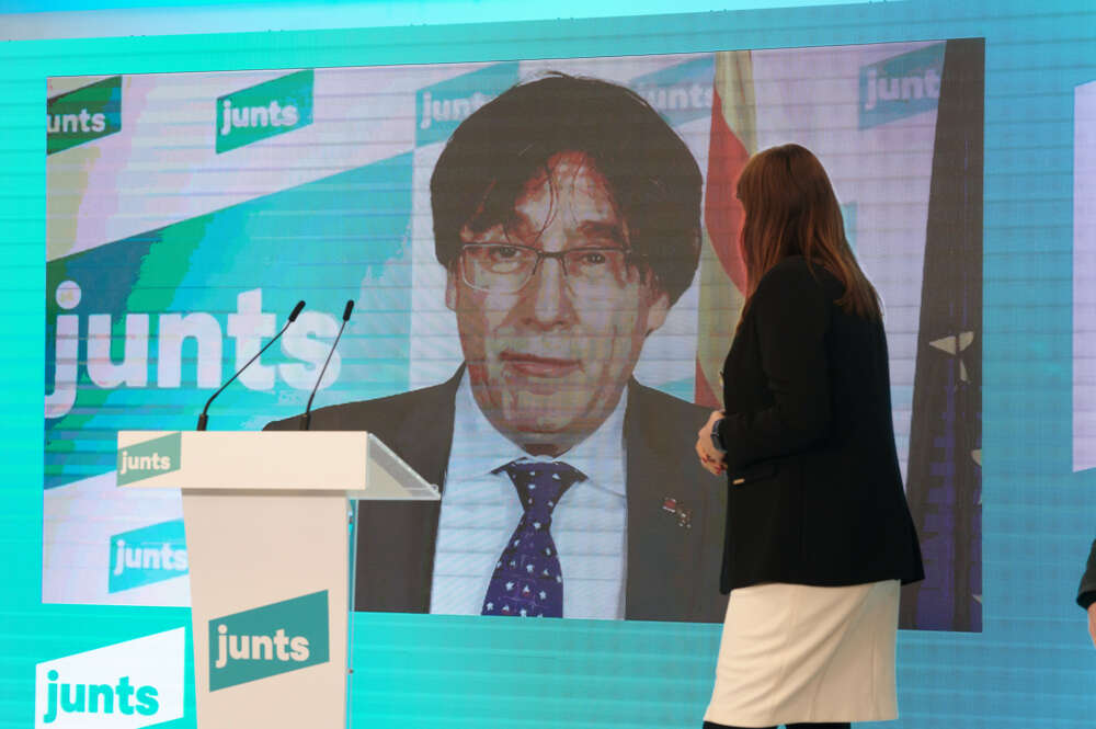 La líder de Junts per Catalunya en el Parlament, Laura Borràs, frente a una pantalla con el prófugo Carles Puigdemont / JxCat