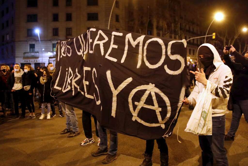 Un grupo de anarquistas luce este sábado una pancarta con el lema: "Os queremos libres ya"./ EFE/ Marta Pérez