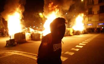 Un manifestante con contenedores ardiendo detrás en la cuarta noche de protestas por la detención del rapero Pablo Hasél, el 19 de febrero de 2021 en Barcelona | EFE/QG/Archivo