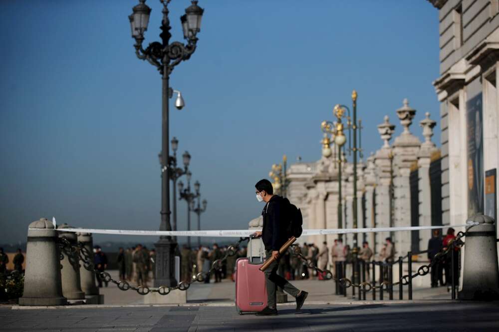 Un joven con su maleta pasa ante el Palacio Real de Madrid. EFE/ Juan Carlos Hidalgo/Archivo