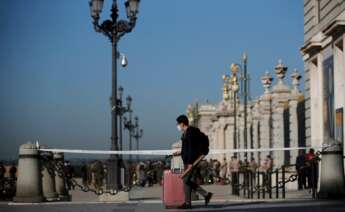 Un joven con su maleta pasa ante el Palacio Real de Madrid. EFE/ Juan Carlos Hidalgo/Archivo