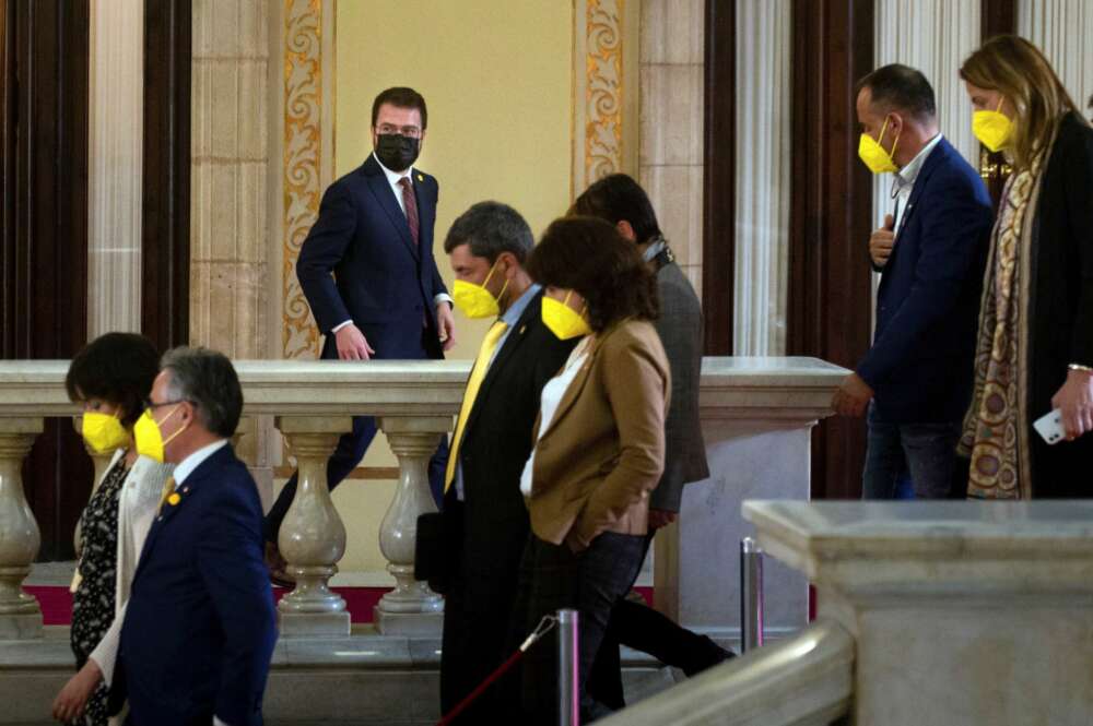 El candidato de ERC, Pere Aragonés, junto a varios diputados de JxCat, en los pasillos del Parlament durante un receso del debate de investidura del nuevo presidente de la Generalitat que se celebra este viernes en el Auditori del Parlament de Catalunya. EFE/Enric Fontcuberta