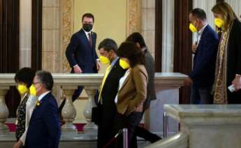 El candidato de ERC, Pere Aragonés, junto a varios diputados de JxCat, en los pasillos del Parlament durante un receso del debate de investidura del nuevo presidente de la Generalitat que se celebra este viernes en el Auditori del Parlament de Catalunya. EFE/Enric Fontcuberta