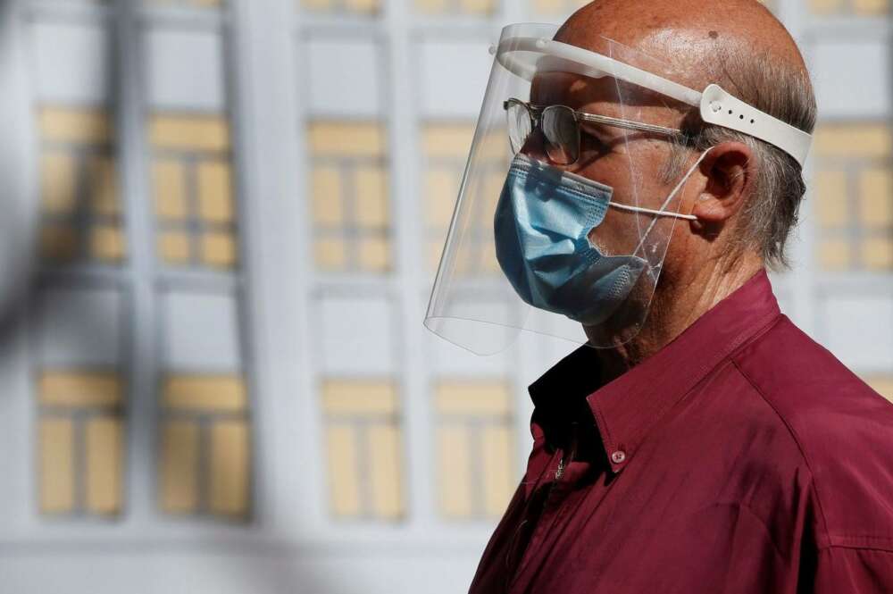 Un hombre se protege del coronavirus con una pantalla y mascarilla./ EFE