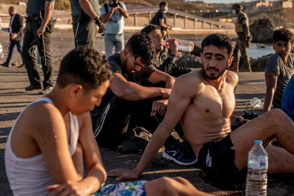 Varios migrantes descansan en la playa ceutí de El Tarajal tras alcanzar la costa española este miércoles. Tercer día de tensión en la frontera de Ceuta con Marruecos, después de la entrada ilegal en la ciudad autónoma de más de 8.000 personas y con el Ejército y las fuerzas de seguridad desplegados en la zona. EFE/Brais Lorenzo