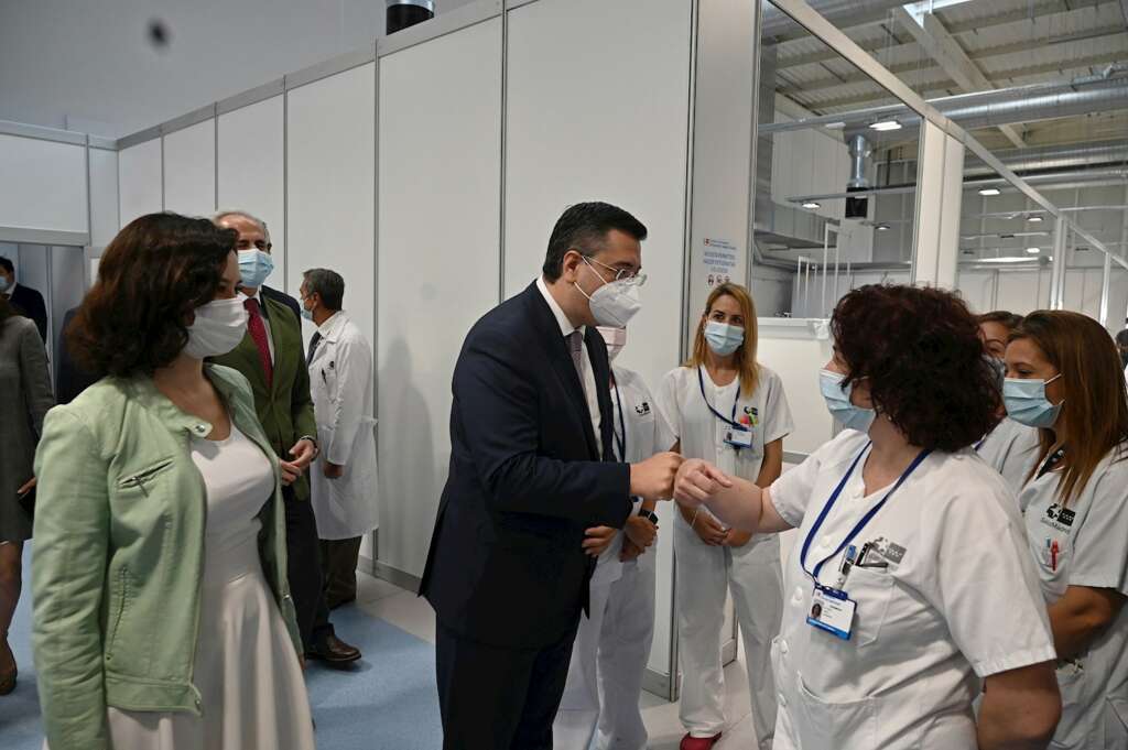 El presidente del Comité Europeo de las Regiones, Apostolos Tzitzikostas (c), saluda a varias trabajadoras mientras visita, junto a la presidenta de Madrid, Isabel Díaz Ayuso (i), el Hospital Enfermera Isabel Zendal, que atiende a pacientes con coronavirus, este jueves en Madrid. EFE/Fernando Villar