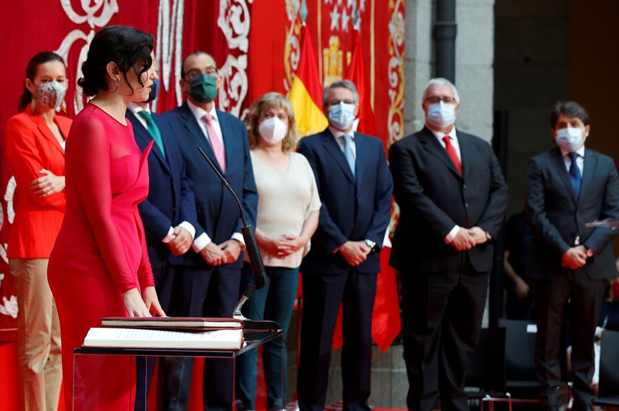 La presidenta de la Comunidad de Madrid, Isabel Díaz Ayuso (i) jura su cargo durante su investidura celebrada en la Real Casa de Correos este sábado. EFE/J.J. Guillén