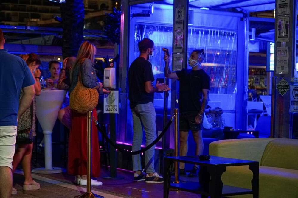 Un empleado toma la temperatura a un joven que hace cola para entrar en un pub en el puerto deportivo de Marbella. EFE/Antonio Paz/Archivo