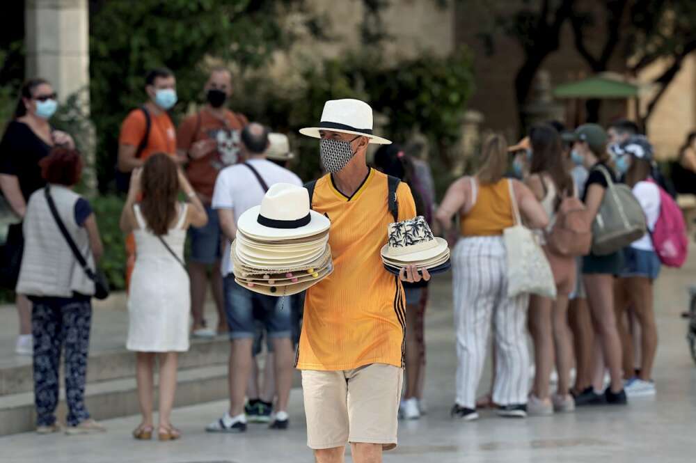 La mitad de los españoles no confía en que la recuperación llegue en 2023. En la imagen, un hombre vende sombreros en una calle de Valencia. EFE/ Biel Aliño/Archivo