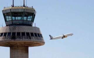 En la imagen, un avión despega ante la torre de control del aeropuerto de El Prat. / EFE