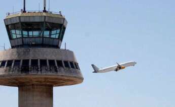 En la imagen, un avión despega ante la torre de control del aeropuerto de El Prat. / EFE
