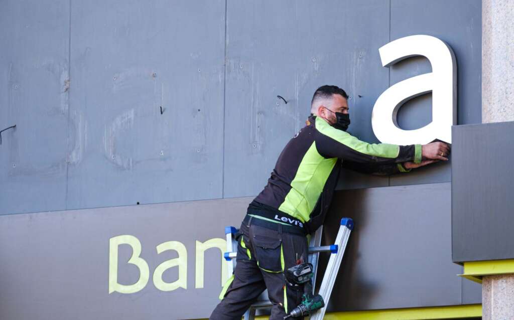 GRAF2964. LOGROÑO, 27/03/2021.- Los operarios desmontan el rótulo de Bankia de la sede principal del banco en Logroño este sábado tras iniciar CaixaBank su andadura, una vez culminado el proceso legal de fusión con Bankia. EFE/Abel Alonso