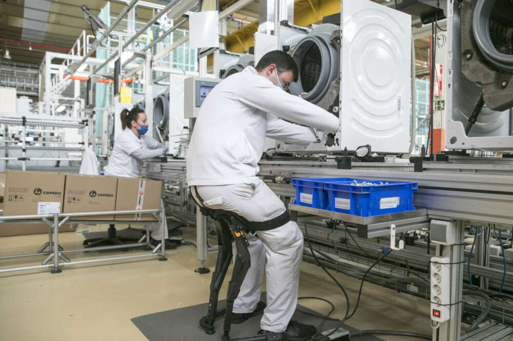 ZARAGOZA, 28/03/2022.- Un trabajador utiliza un exoesqueleto para mejorar la ergonomía en su puesto de la fábrica de lavadoras que BSH tiene en La Cartuja (Zaragoza). BSH España, ante su candidatura a los Galardones Europeos a las Buenas Prácticas 2022, ha abierto hoy sus puertas a autoridades y medios de comunicación. EFE/Javier Cebollada.