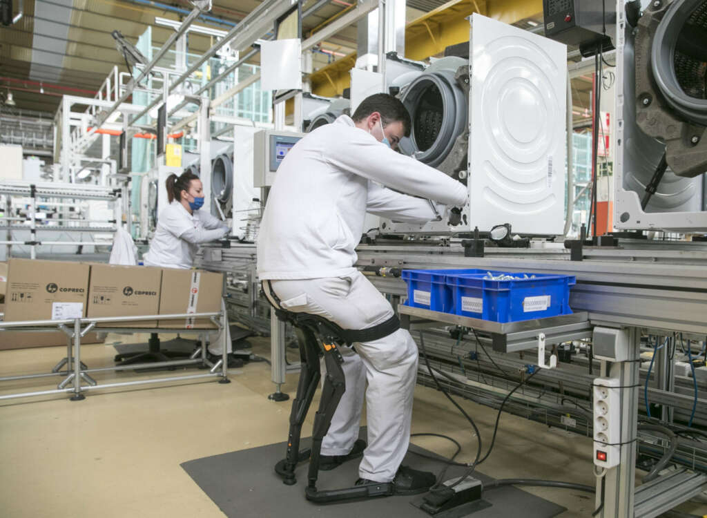 ZARAGOZA, 28/03/2022.- Un trabajador utiliza un exoesqueleto para mejorar la ergonomía en su puesto de la fábrica de lavadoras que BSH tiene en La Cartuja (Zaragoza). BSH España, ante su candidatura a los Galardones Europeos a las Buenas Prácticas 2022, ha abierto hoy sus puertas a autoridades y medios de comunicación. EFE/Javier Cebollada.