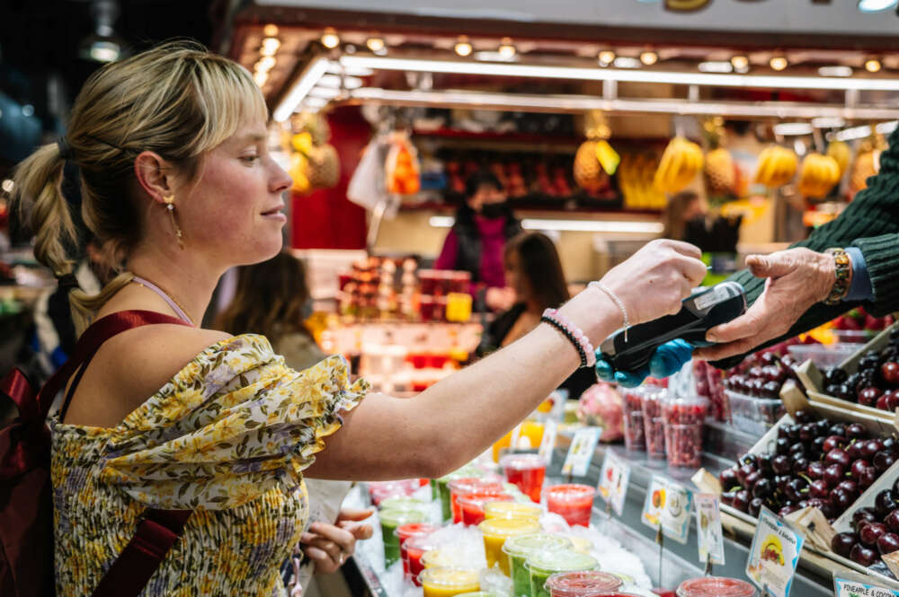 Una mujer comprando en un comercio local.