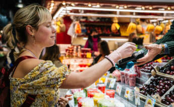 Una mujer comprando en un comercio local.