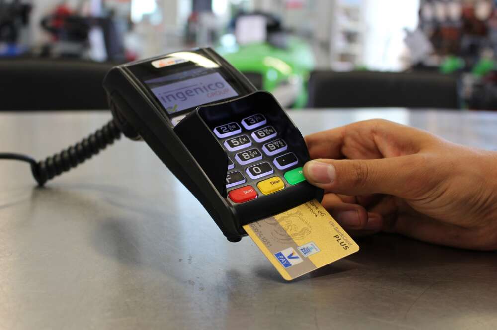 Una persona hace un pago en un datáfono con una tarjeta