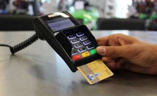 Una persona hace un pago en un datáfono con una tarjeta