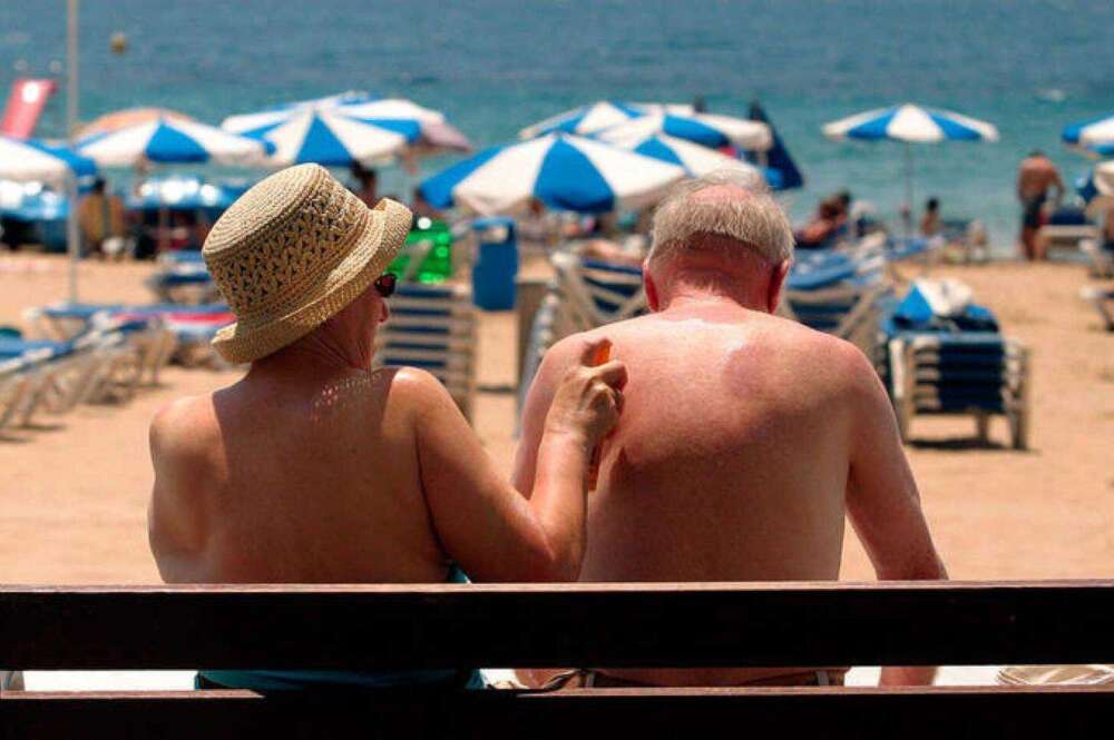Dos jubilados toman el sol en la playa. Foto: EFE.