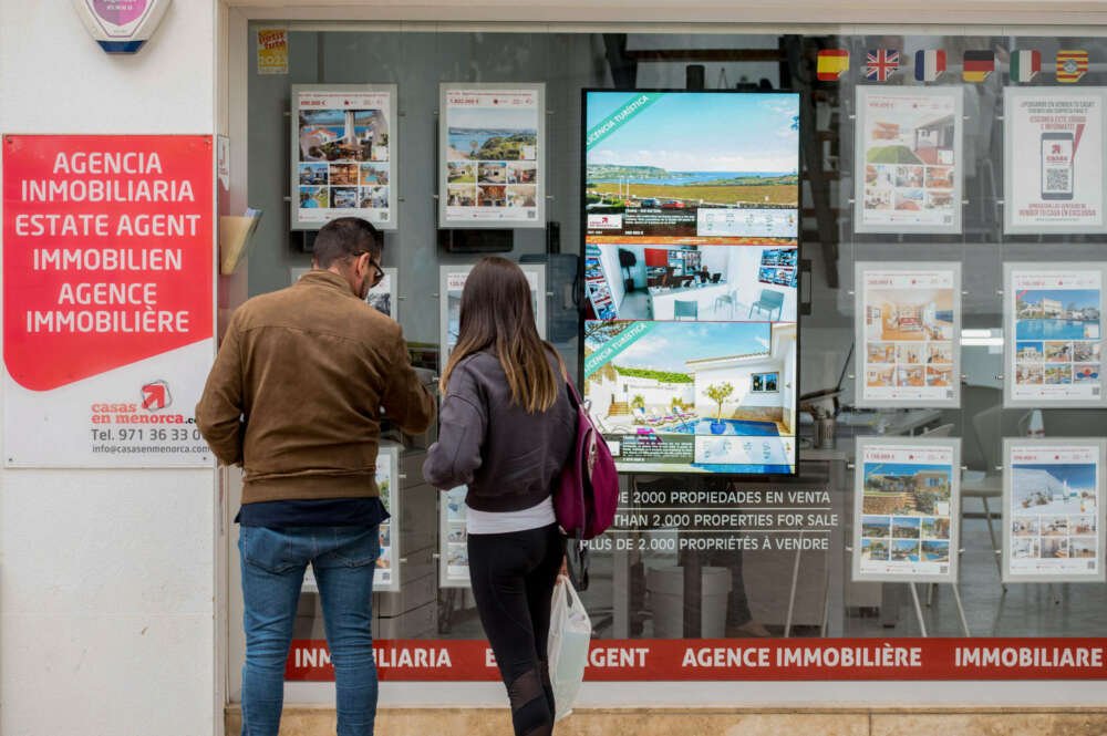 GRAF7499. MENORCA (ISLAS BALEARES), 11/05/2023.- Una pareja se detiene a observar las propiedades en venta anunciadas en el escaparate de una agencia inmobiliaria de Menorca, este jueves. El precio medio de la vivienda nueva y usada en Baleares en el primer trimestre del año fue de 3.027 euros por metro cuadrado, un 7 % menos que en el último cuarto de 2022, un coste de mercado un 57,5 % por encima del promedio estatal. En el conjunto de España, la compraventa de viviendas se redujo un 2 % en el primer trimestre del año, un periodo en el que los precios se incrementaron un 4,9 % en tasa interanual, según los datos publicados hoy por el Colegio de Registradores. EFE/ David Arquimbau Sintes