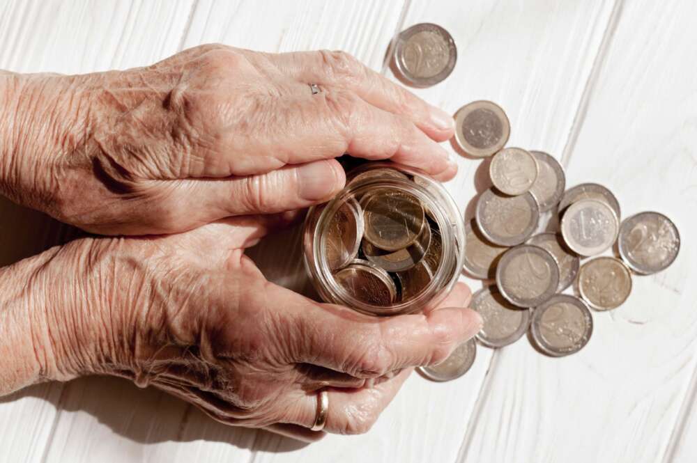 Una persona sostiene un tarro con monedas entre sus manos