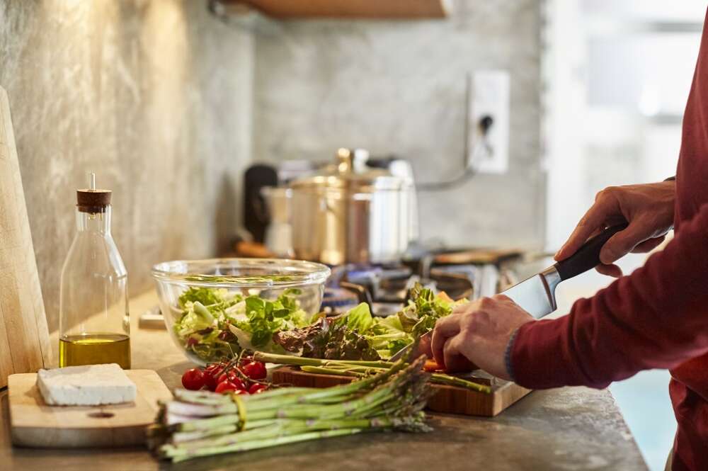 Una persona corta alimentos sobre una tabla de madera