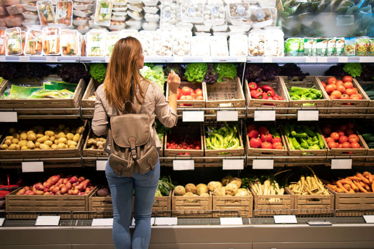 Una chica mira los estantes de fruta de un supermercado