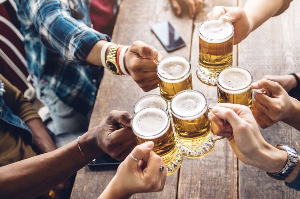 Varios amigos brindan en una mesa con jarras de cerveza