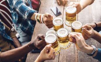 Varios amigos brindan en una mesa con jarras de cerveza