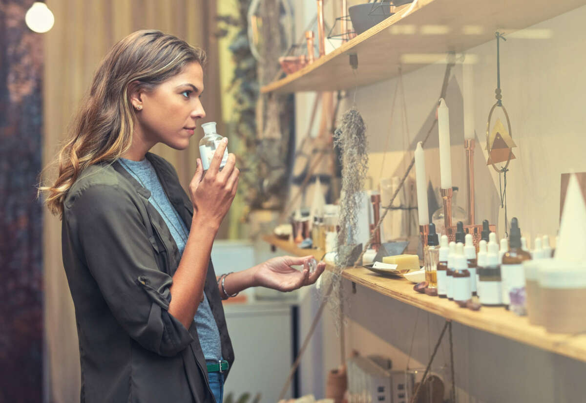 Una mujer huele un bote de perfume