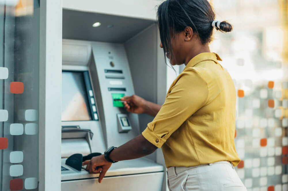 Una señora saca dinero del cajero con su tarjeta de crédito
