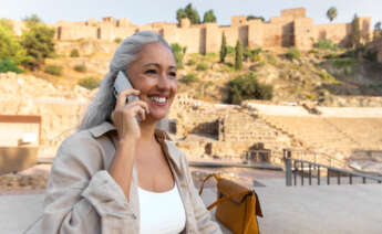 Una persona habla por teléfono mientras visita un monumento histórico. Foto: Freepik.