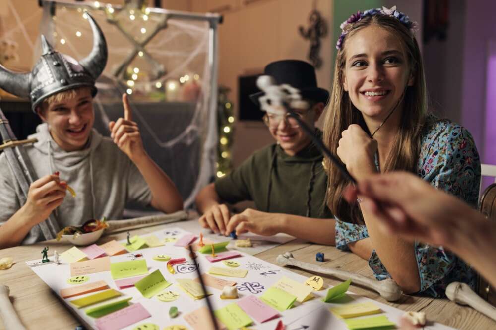 Unos niños juegan a unos juegos de mesa disfrazados de Halloween