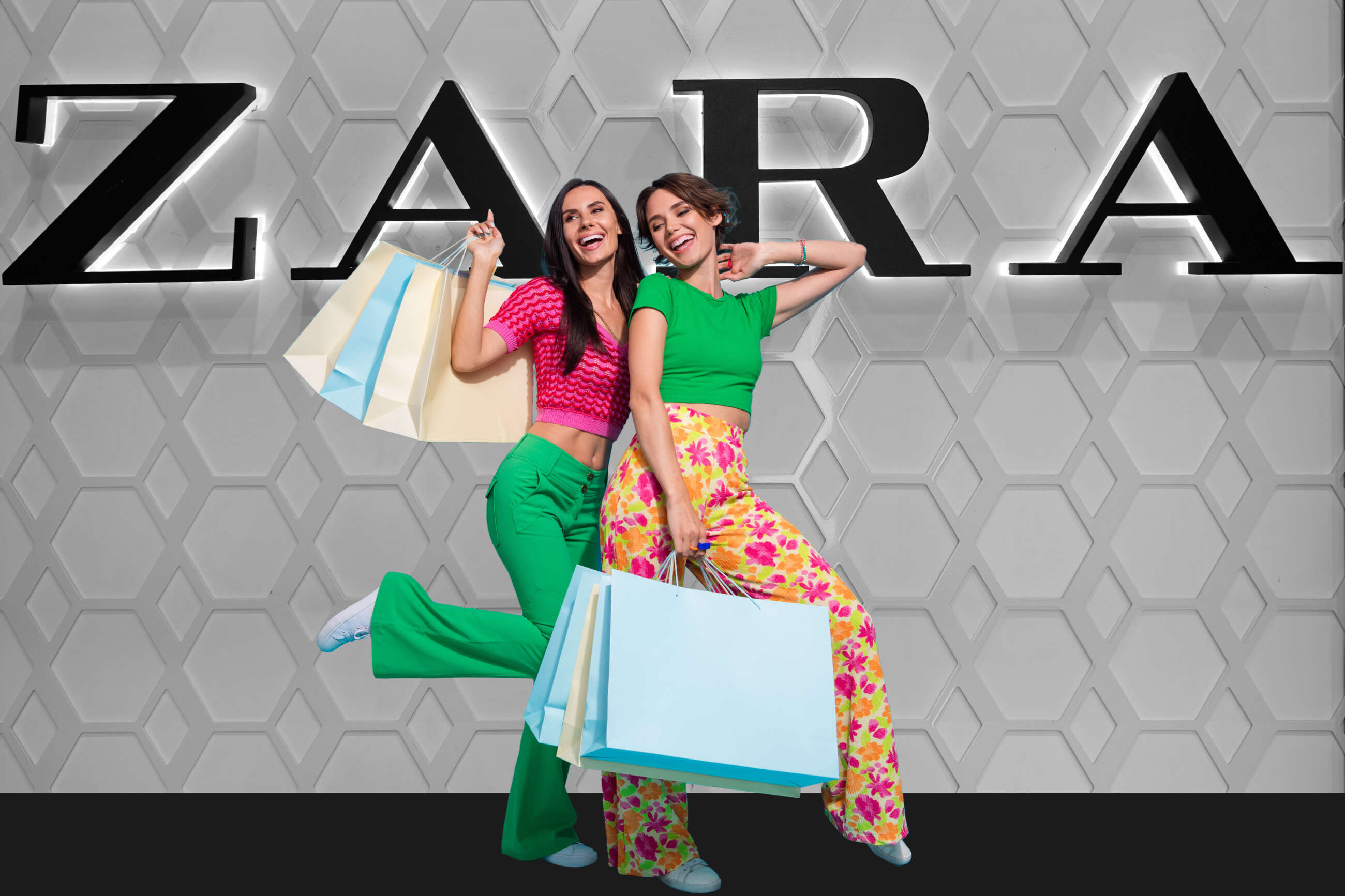 Dos chicas con bolsas de compras delante del logo de Zara