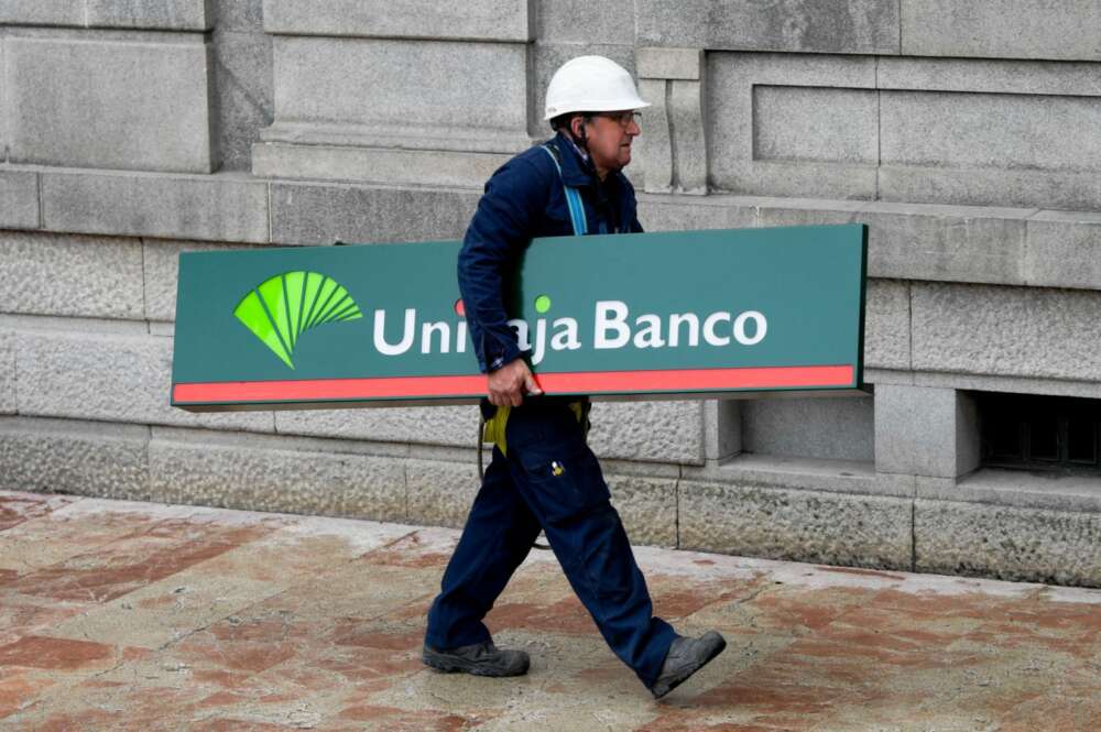 Un operario carga con un cartel de Unicaja Banco para colocarlo en una sucursal de Liberbank en Oviedo.EFE/Eloy Alonso/Archivo.