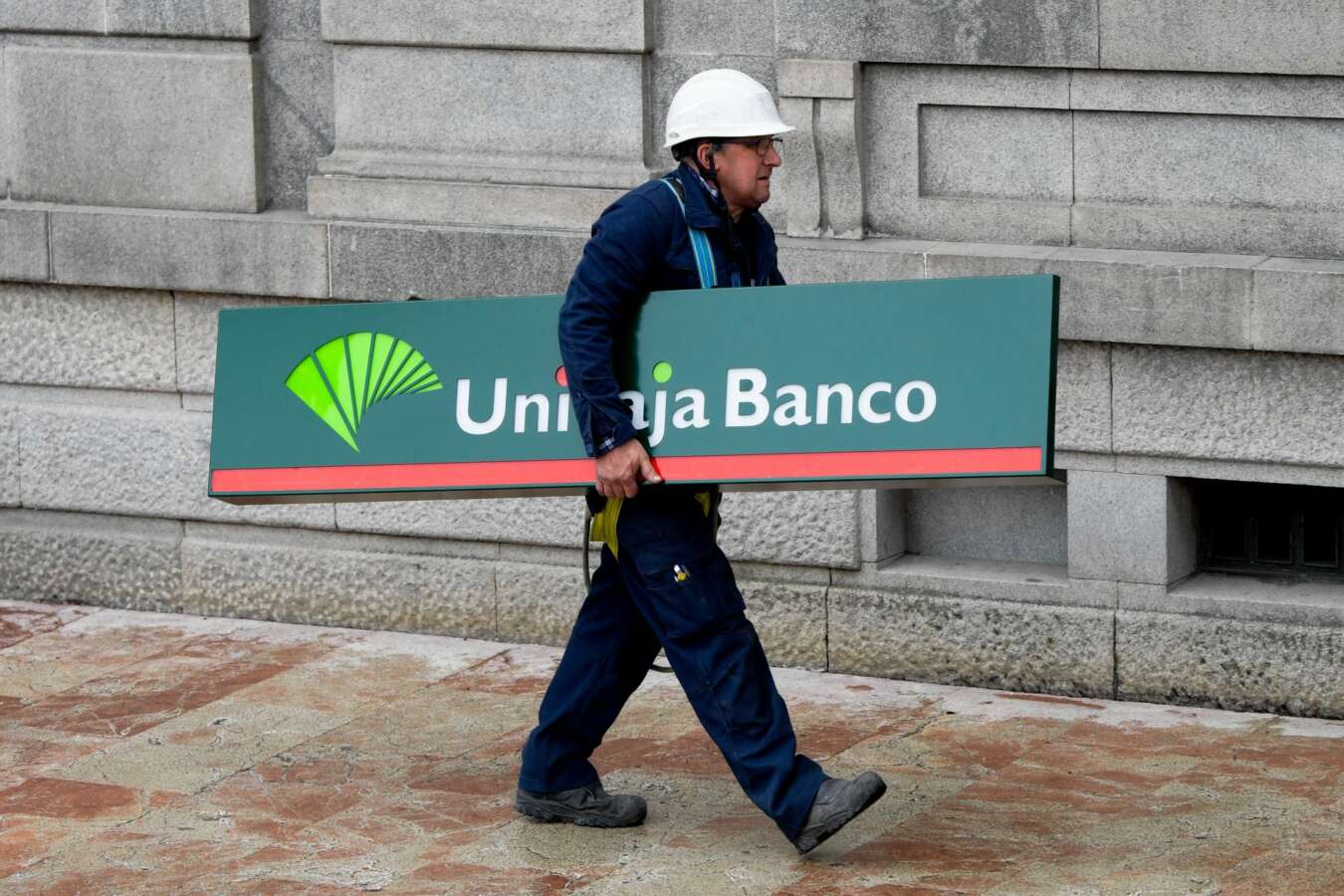 Un operario carga con un cartel de Unicaja Banco para colocarlo en una sucursal de Liberbank en Oviedo.EFE/Eloy Alonso/Archivo.