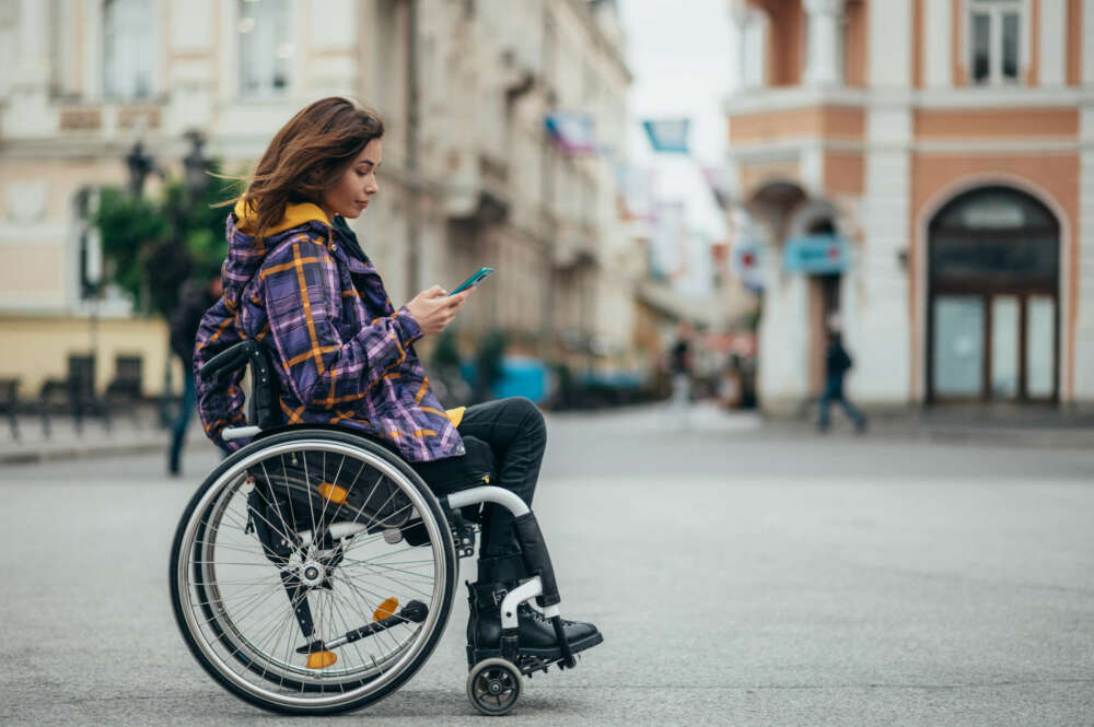 Mujer con discapacidad usando su teléfono mientras está en la ciudad