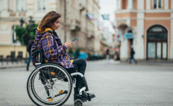 Mujer con discapacidad usando su teléfono mientras está en la ciudad