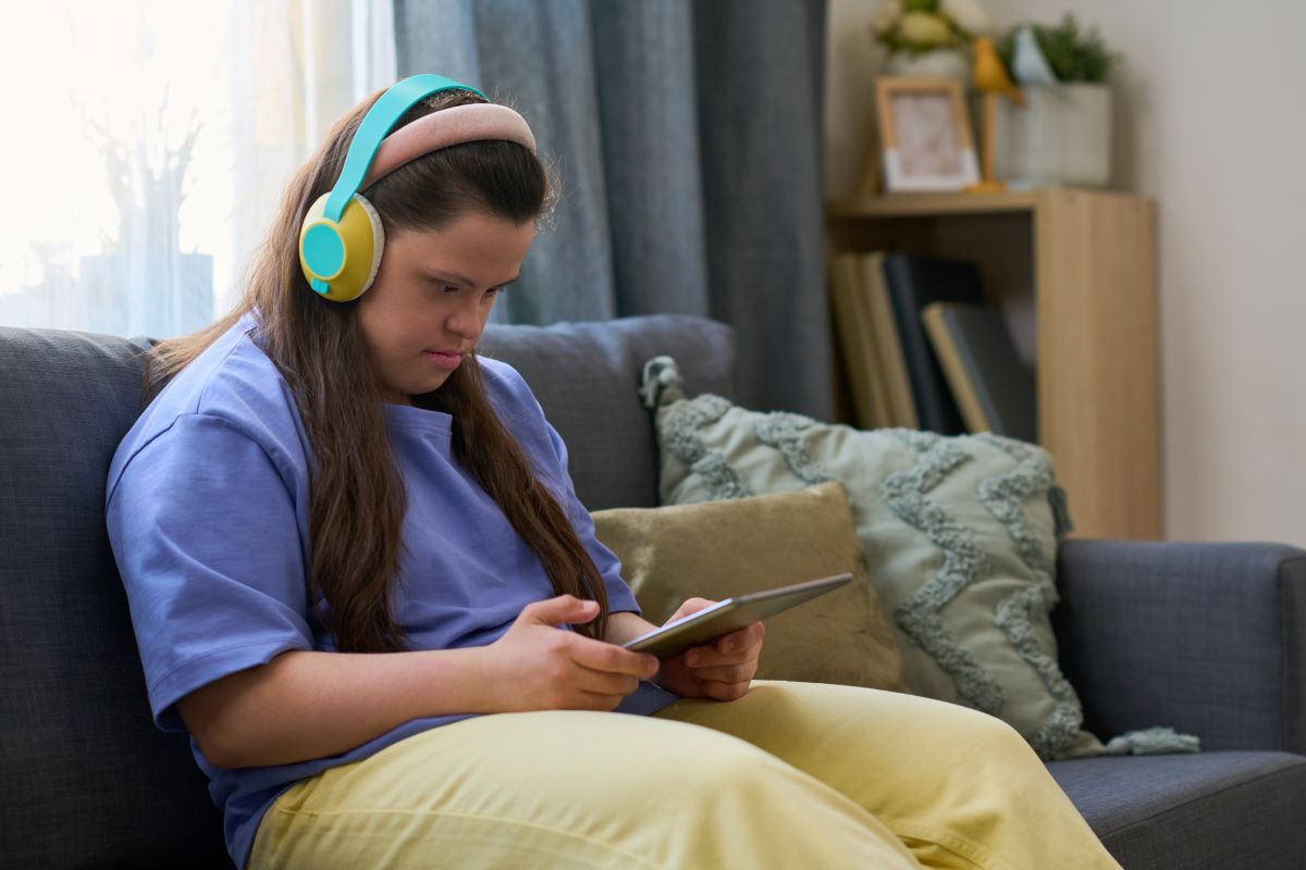 Mujer joven con discapacidad viendo una película online en la sala de estar