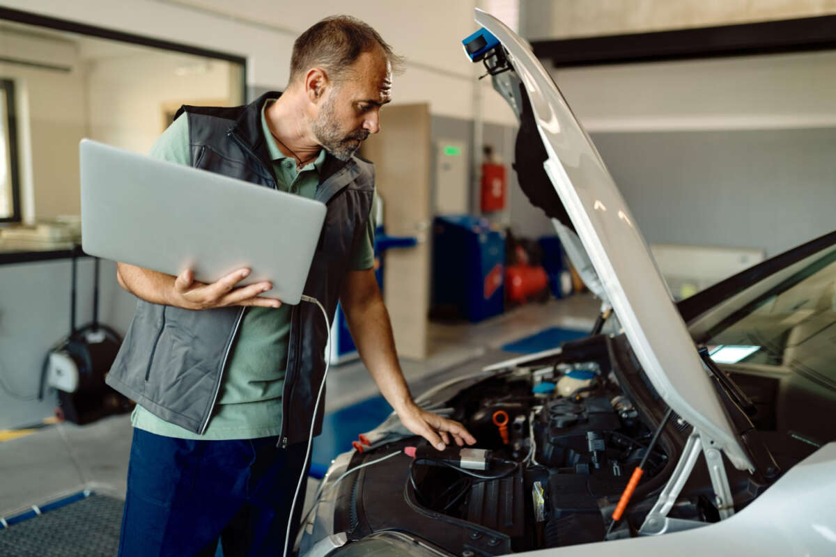 Un trabajador autónomo de un taller revisa el coche de un cliente