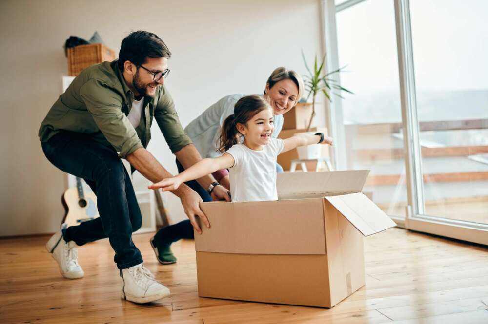 Una familia juega con una niña en la casa con la caja de la mudanza. Foto: Freepik.