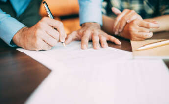 Una persona firmando un documento.