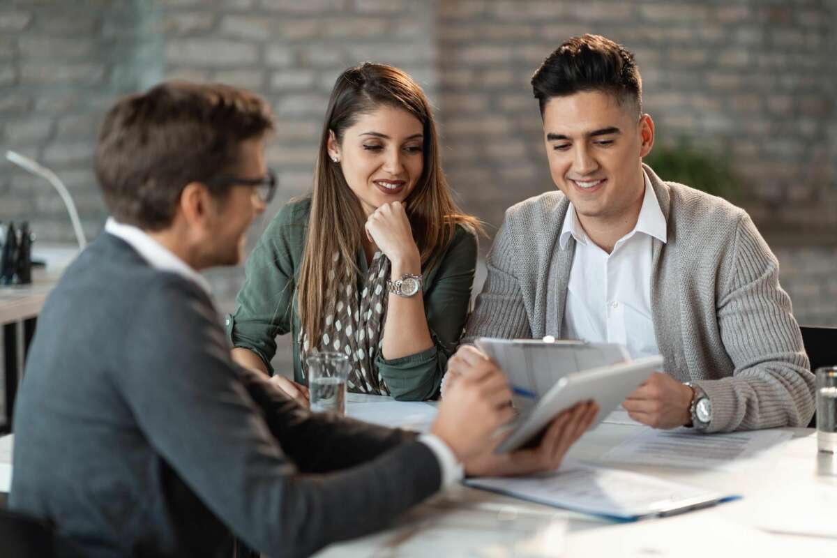 Un trabajador del banco detalla a una pareja las condiciones de una hipoteca. Foto: Freepik.