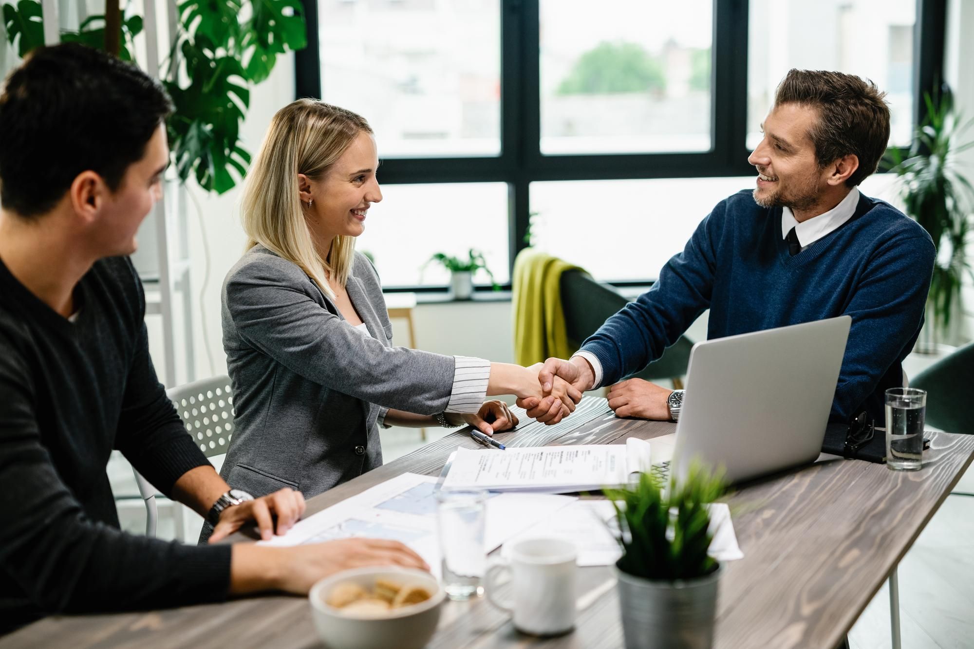 Una trabajadora de un banco estrecha la mano de una pareja que acaba de firmar una hipoteca. Foto: Freepik.