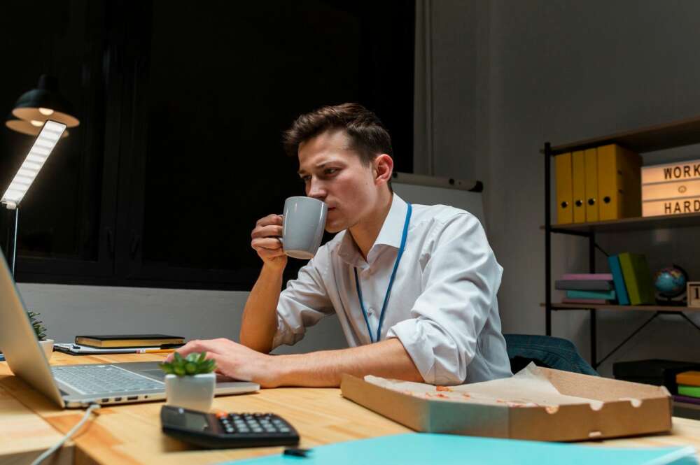 Un autónomo trabaja frente a su ordenador mientras bebe un café. Foto: Freepik.