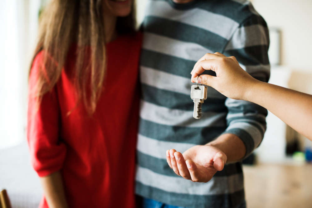 Una persona entrega unas llaves a una pareja. Foto: Freepik.