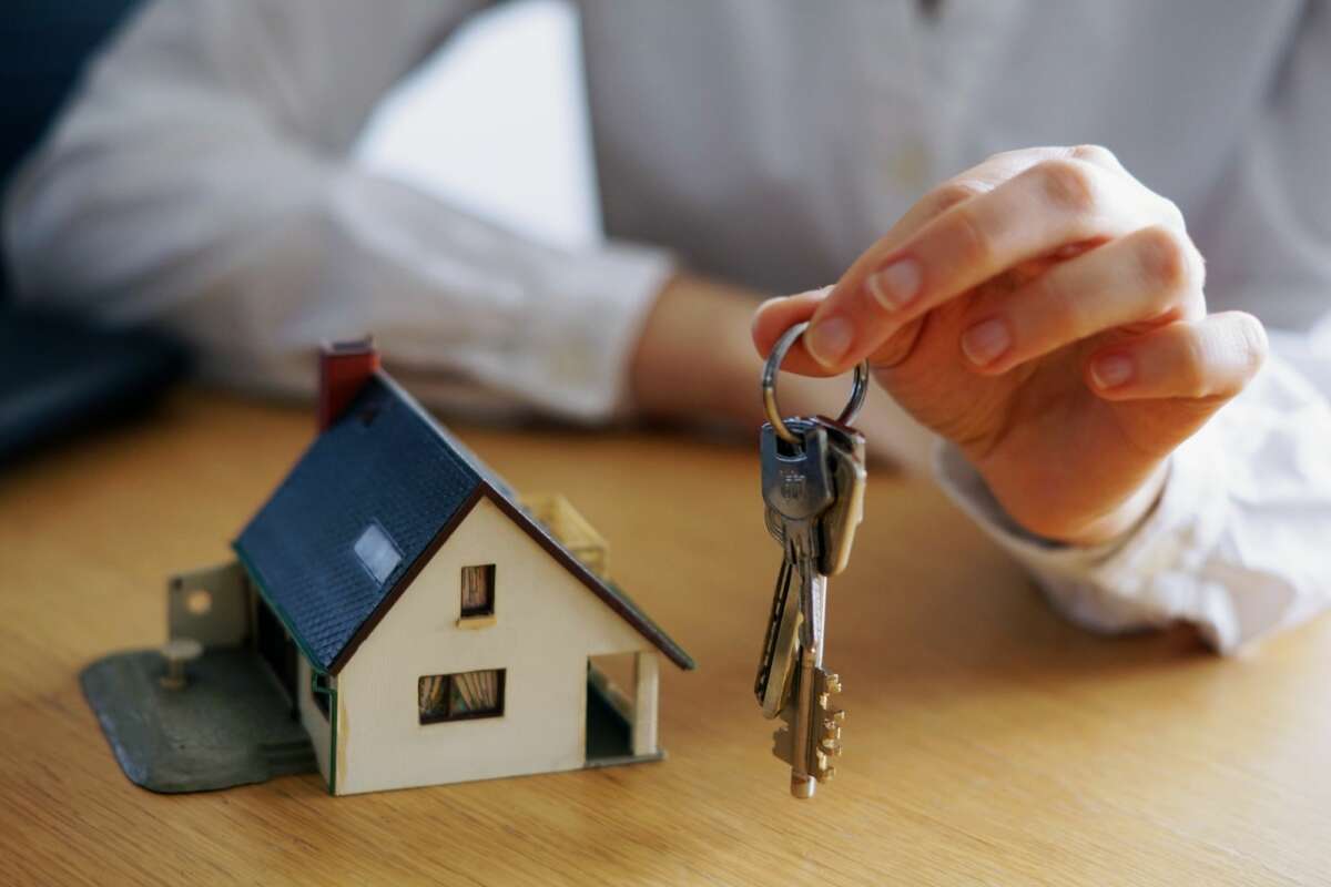 Una persona sostiene unas llaves junto a una vivienda de madera. Foto: Freepik.